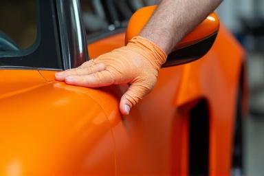 एक कार पर नारंगी रैप लगाया जा रहा है